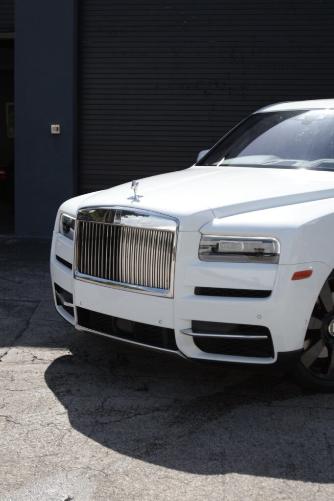 A white rolls royce parked in front of a building.