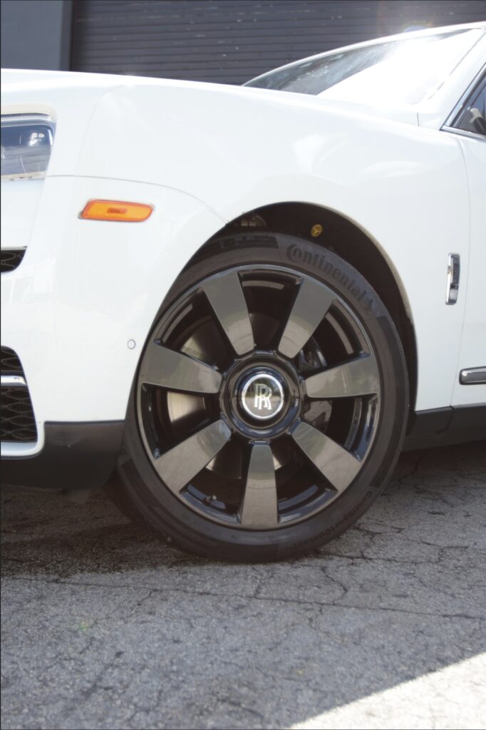 A white car with black rims parked on the street.