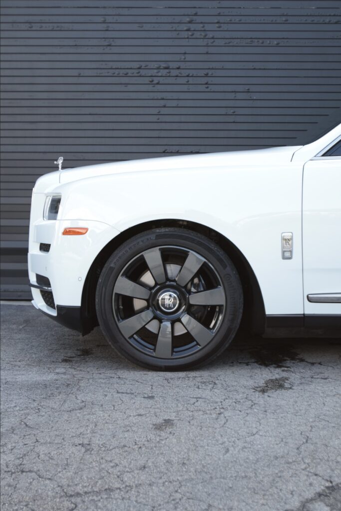 A white car with black rims parked in front of a building.